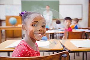 Cute pupil smiling at camera in classroom
