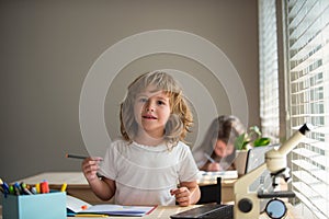 Cute pupil writing at desk in classroom at the elementary school. Student boy doing test in primary school. Children