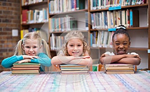 Cute pupils smiling at camera in library