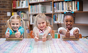 Cute pupils smiling at camera in library