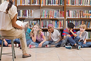 Cute pupils and teacher having class in library