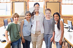 Cute pupils and teacher smiling at camera in computer class