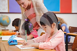 Cute pupils writing at desk in classroom