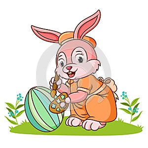 The cute rabbit is coloring the ester egg