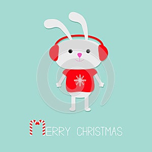 Cute rabbit in red pullover with snowflake. Headphone hat. Candy cane. Merry Christmas Greeting Card. Blue background. Flat design