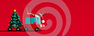 Cute red car with deer antlers on the roof carrying green paper Christmas tree on red background