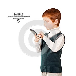 Cute red haired child stands looking at the smartphone. Isolated