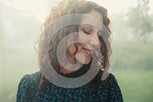 Cute red-haired curly girl rejoices under the water fogger in the city center photo