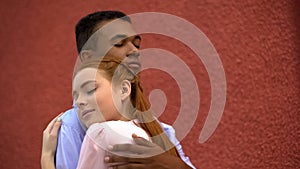 Cute red-haired girl snuggling to her mixed-race boyfriend, couple hugging