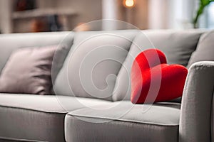 Cute red heart on a white sofa, blurred background.