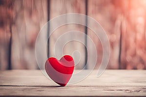 Cute red heart on a wooden table and wooden blurred background.