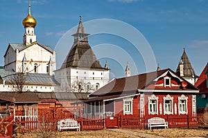 Cute red wooden house with white carved platbands surrounded by a wooden palisade in Rostov the Great.