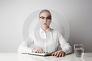 Cute redhead business woman working at the table over empty white background.