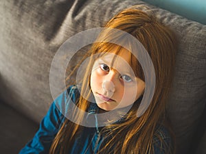 Cute redhead little girl looking at us serious