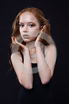 Cute redhead teenage model with bright makeup and colorful glitter and sparkles on her face and body.