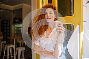 Cute redhead woman with long hair holding cup of coffee