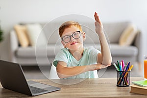 Cute redheal boy schooler raising hand up