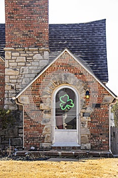 Cute rock cottage with arched front door with shamrock wreath for St Patricks Day of metal storm door