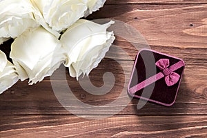 Cute romantic image with luxury white roses and velvet gift box on the wooden surface. Wedding proposal.