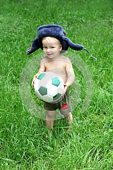 Cute Russian toddler boy in a ushanka hat is holding a soccer or