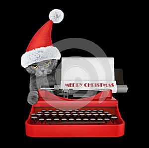 Cute santa cat is typing on a typewriter keyboard. Isolated on black