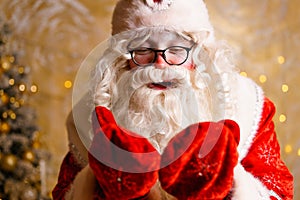 Cute santa claus in glasses on a wall background with a bright garland bokeh