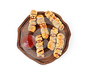 Cute sausage mummies served with ketchup isolated on white, top view. Halloween party food