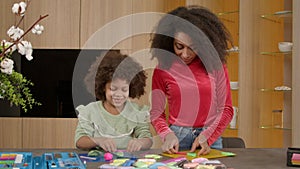 Cute school age African American girl and mother molding from colorful play clay