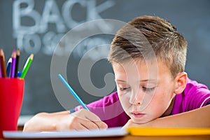 Cute school boy studying in classroom