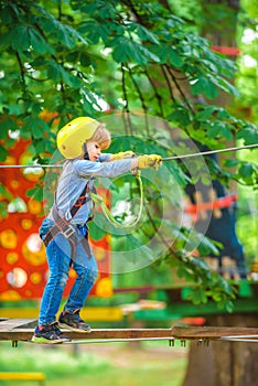 Cute school child boy enjoying a sunny day in a climbing adventure activity park.