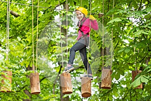 Cute school child boy enjoying a sunny day in a climbing adventure activity park. Children summer activities. Roping