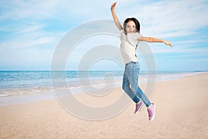 School girl jumping on beach near sea, space for text. Summer holidays