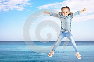 School girl jumping near sea, space for text. Summer holidays