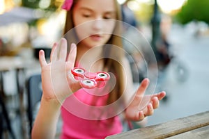 Cute school girl playing with colorful fidget spinner