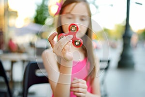 Cute school girl playing with colorful fidget spinner