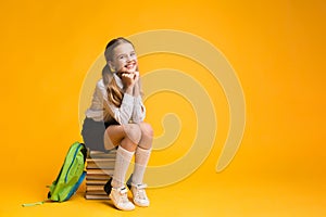 Cute School Girl Sitting On Book Stack On Yellow Background