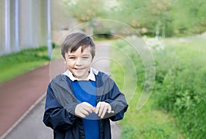 Cute School kid holding dandelion flower in spring park while walking to school in the morning. Happy child boy having fun