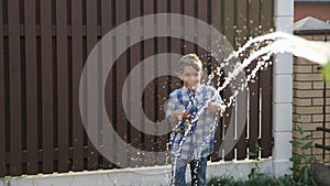 Cute schoolboy enjoys drops flowing from water gun jet