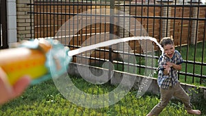 Cute schoolboy enjoys drops flowing from water gun jet