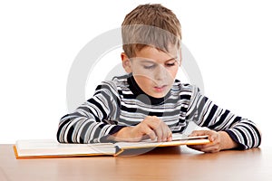 Cute schoolboy is reading a book