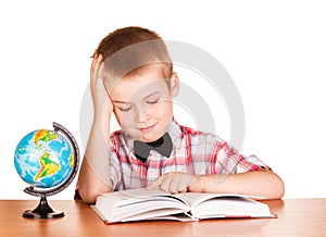 Cute schoolboy reading book, globe isolated on white.