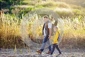 Cute schoolchild and his mature father hiking together and exploring nature. Child learning survival skills and orienteering.