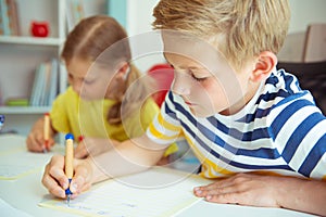 Cute schoolchildren are came back to school and learning at the table in classroom