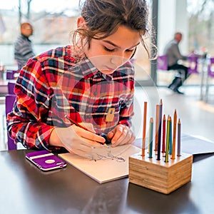 Cute schoolgirl drawing with pencils.