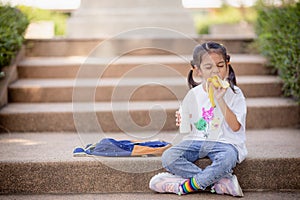 Cute schoolgirl eating outdoors the school. Healthy school breakfast for children. Food for lunch