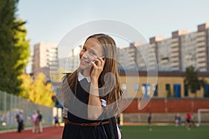 Cute schoolgirl with smartphone outdoors photo