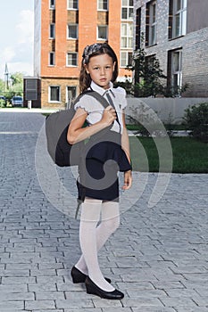 Cute schoolgirl in uniform standing in campus photo