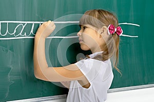 Cute schoolgirl writing on blackboard. Photo session in the studio