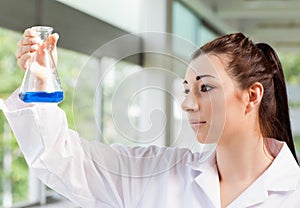 Cute science student looking at a blue liquid