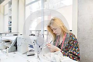 Cute seamstress works in the workplace near a sewing machine. Work place for seamstresses